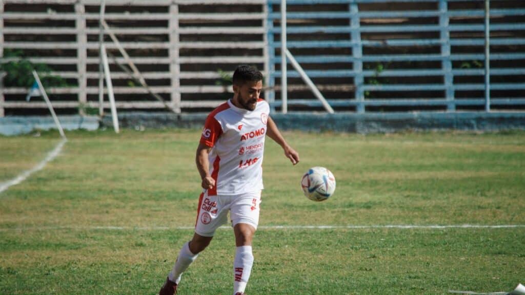 Soccer player in white kit playing on a field in Mendoza, Argentina.