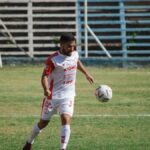 Soccer player in white kit playing on a field in Mendoza, Argentina.
