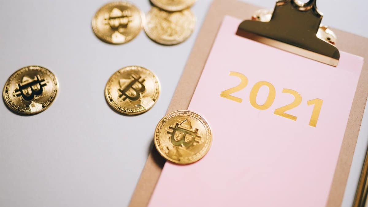 Golden bitcoins scattered around a 2021 clipboard, symbolizing financial planning.