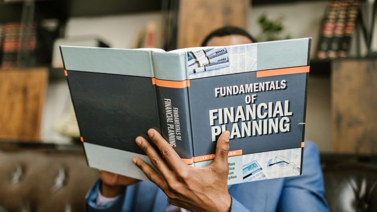 A professional individual in a suit reading 'Fundamentals of Financial Planning' indoors.