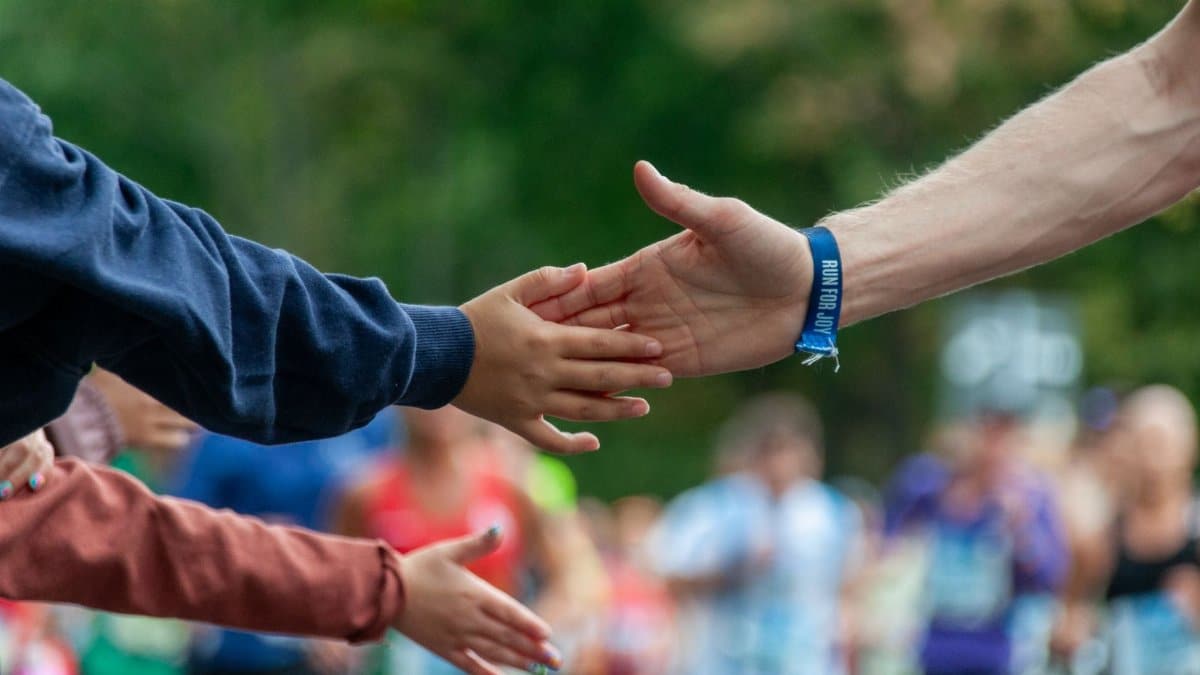 A runner high-fives a spectator during an outdoor marathon, symbolizing support and encouragement.