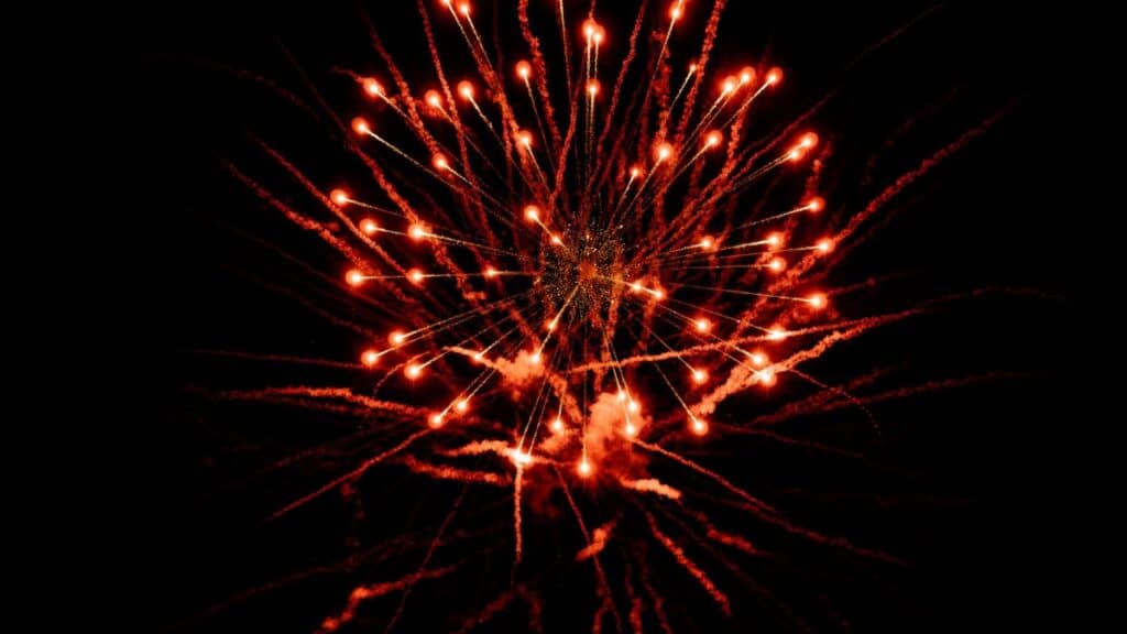 Dramatic red fireworks exploding against a dark night sky, capturing a festive celebration.