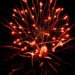 Dramatic red fireworks exploding against a dark night sky, capturing a festive celebration.