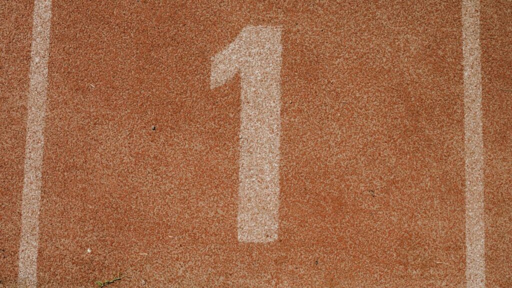 Close-up image of number one lane on a running track, symbolizing first place.