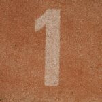 Close-up image of number one lane on a running track, symbolizing first place.