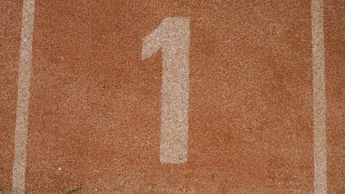 Close-up image of number one lane on a running track, symbolizing first place.