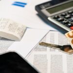Flat lay of financial documents, euro note, calculator, smartphone, and key for budget management.