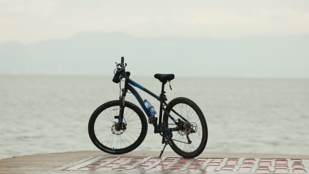 A sleek mountain bike parked by a tranquil lakeside promenade, perfect for outdoor adventure.