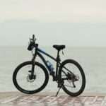 A sleek mountain bike parked by a tranquil lakeside promenade, perfect for outdoor adventure.