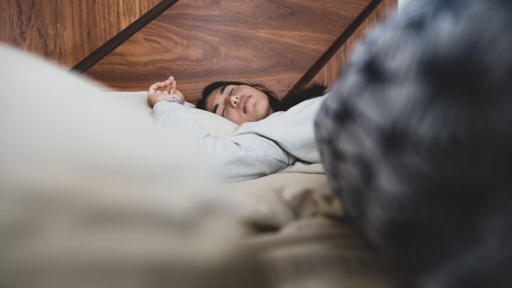 A woman peacefully sleeping on a bed, conveying relaxation and comfort.