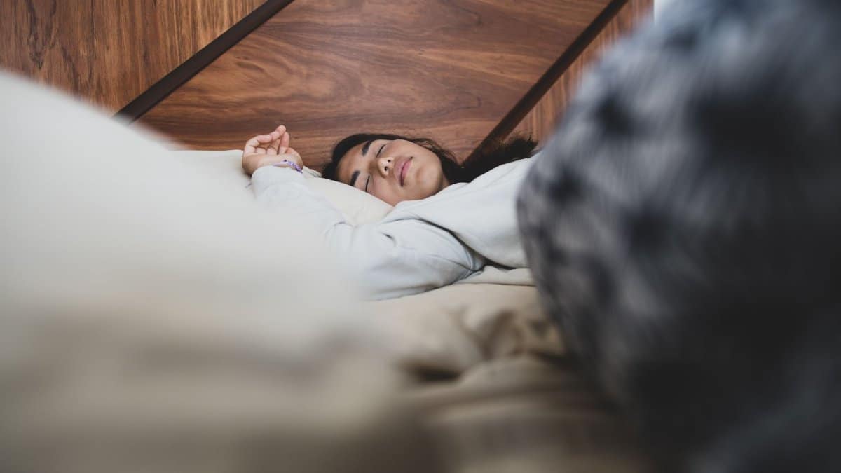 A woman peacefully sleeping on a bed, conveying relaxation and comfort.