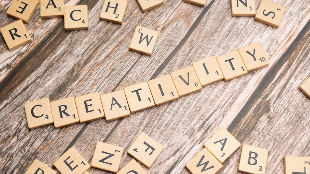 Wooden letter tiles spelling 'creativity' on a rustic wooden background.