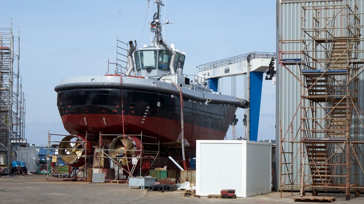 A large ship undergoing repairs in an industrial dockyard setting. Perfect for maritime industry themes.