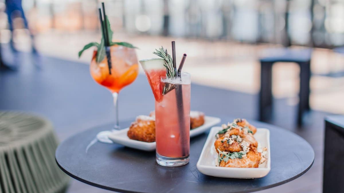 Colorful cocktails and delicious appetizers on a stylish outdoor table, perfect for a summer gathering.