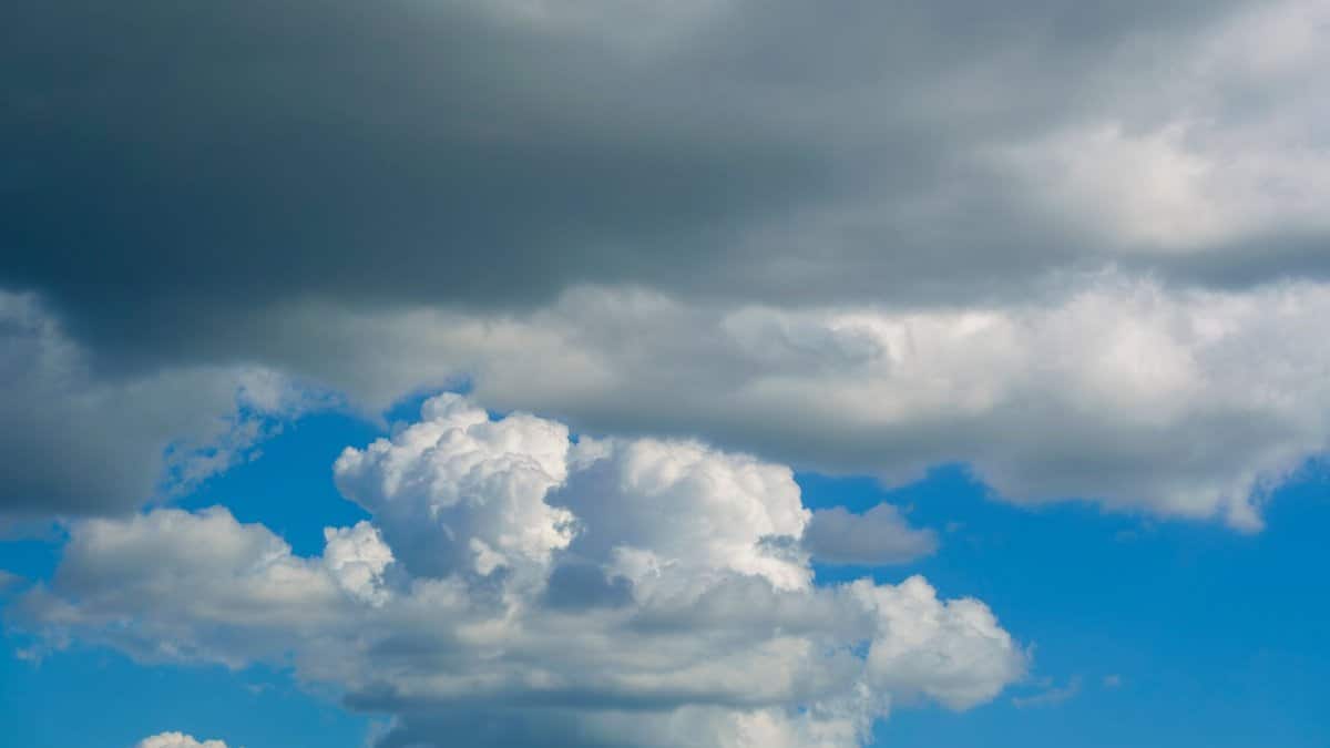 A striking view of cumulus clouds mixed with dark storm clouds against a blue sky.