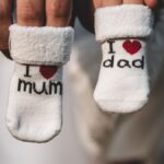 Adorable baby socks with 'I love mum' and 'I love dad' messages held by parents' hands. Perfect for family themes.