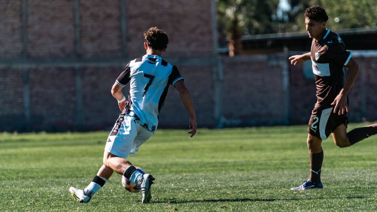 Two soccer players in action during an outdoor daytime match on a grassy field.