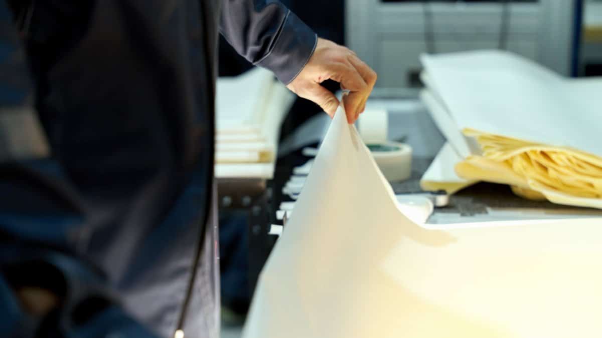 An industrial worker manages large sheets in a manufacturing setting, focusing on precision and quality.