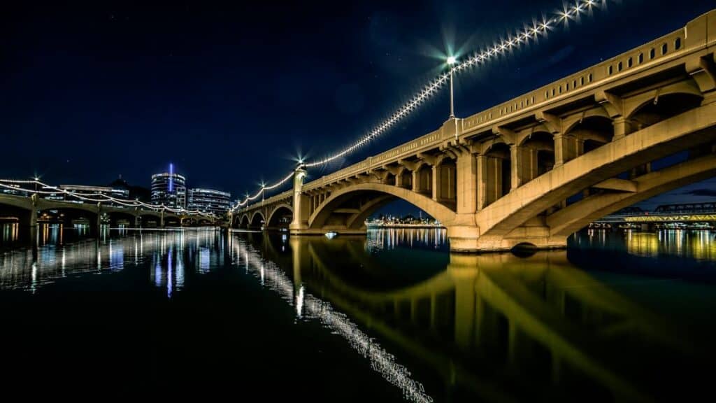 Stunning night view of the illuminated bridge at Tempe Town Lake, Arizona, reflecting in the water.