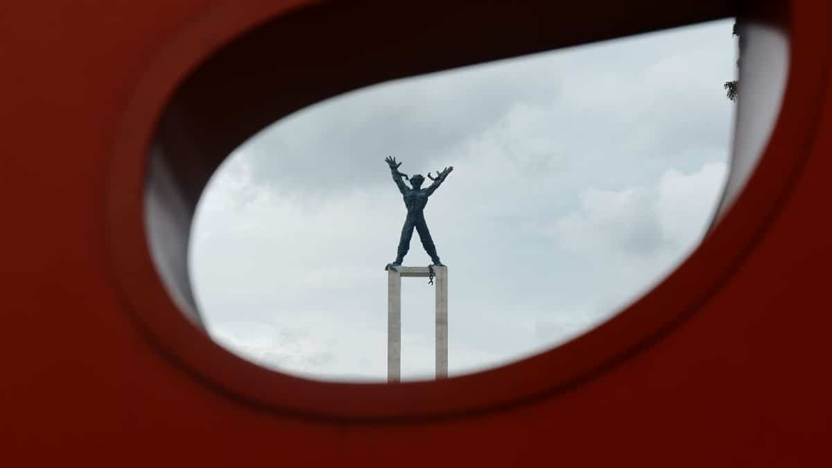 Artistic view of Jakarta's Proclamation Monument framed by a red sculpture, showcasing creativity.