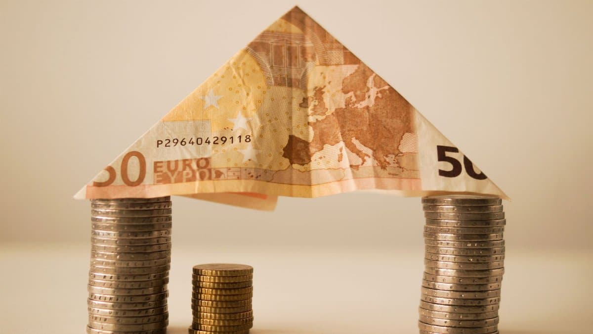A creative composition using euro banknotes and coins to represent savings and financial structure.