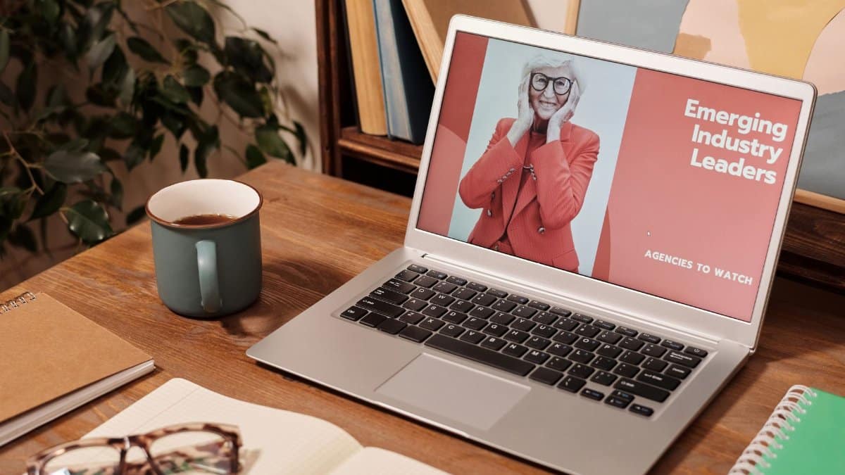 Cozy office desk with a laptop displaying 'Emerging Industry Leaders' and coffee mug.