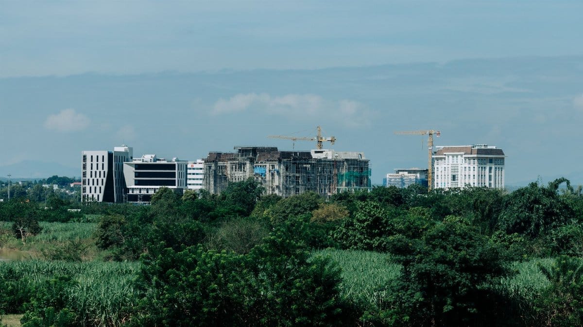 Cityscape of Kon Tum, Vietnam showing urban development amidst greenery with construction cranes.
