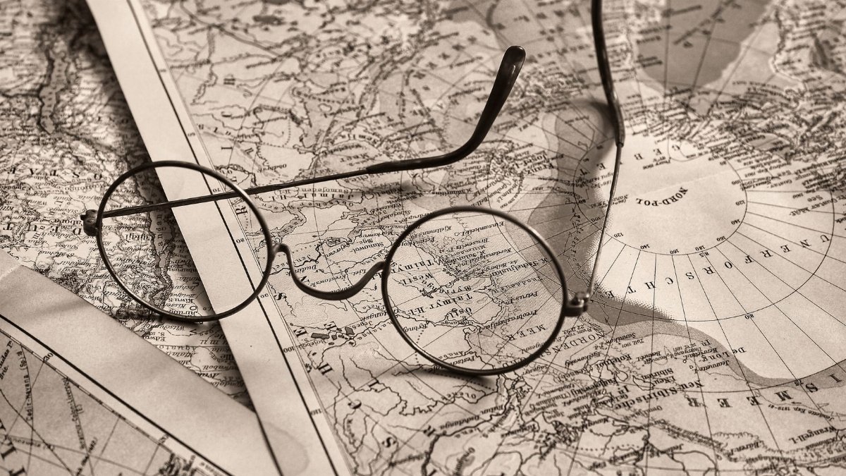 Round eyeglasses rest on an antique world map, evoking a sense of exploration.