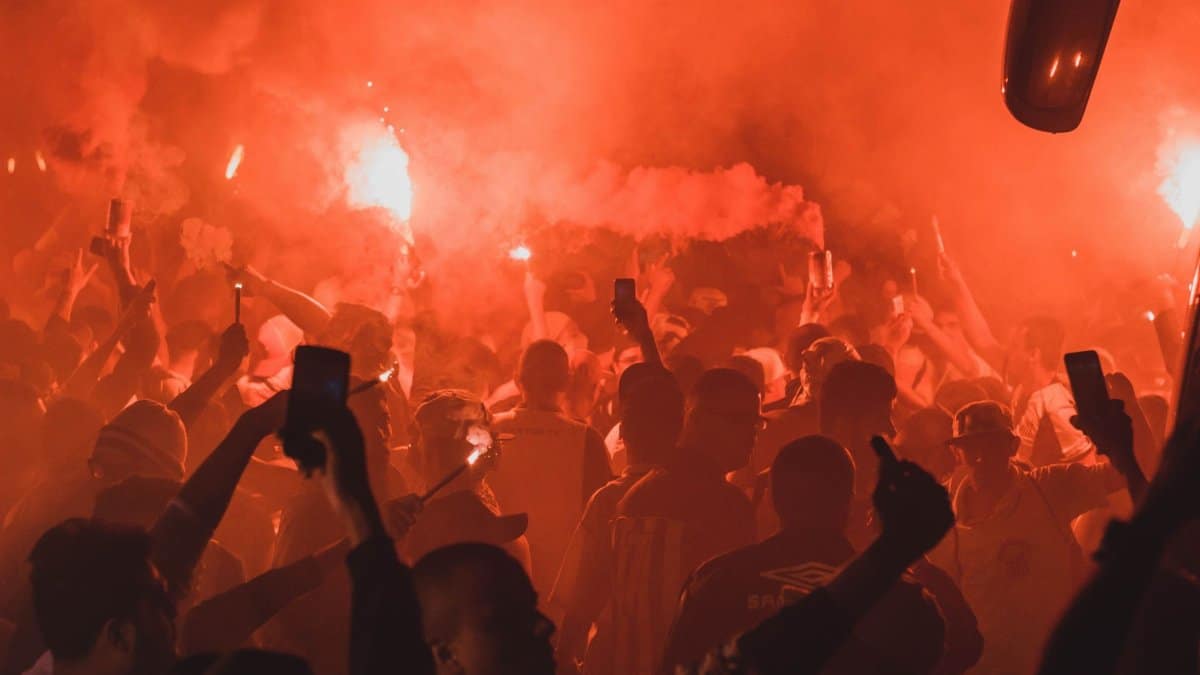 A dynamic crowd enjoying a nighttime party with vibrant flares and smoke, creating a lively atmosphere.