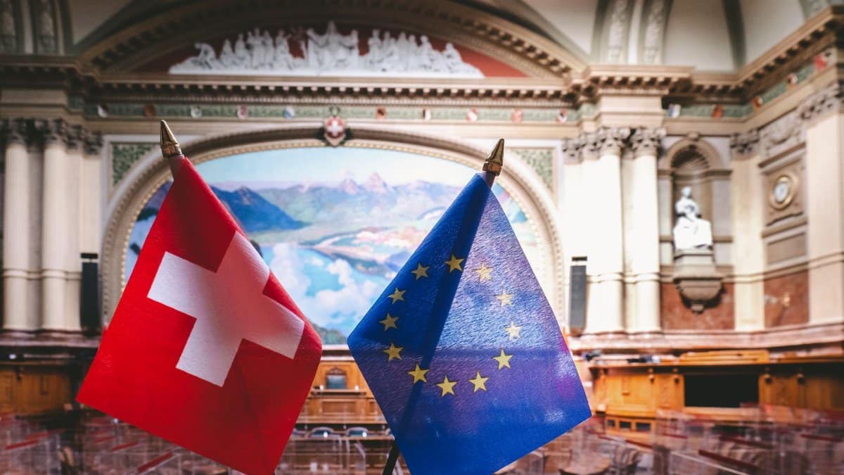 Swiss and EU flags inside the Swiss Parliament building in Bern, showcasing political unity.
