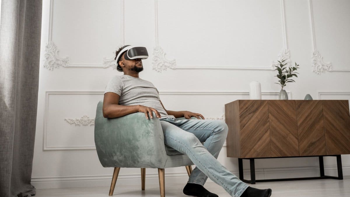 Adult man sitting in a stylish room, wearing a VR headset, showcasing modern technology and relaxation.