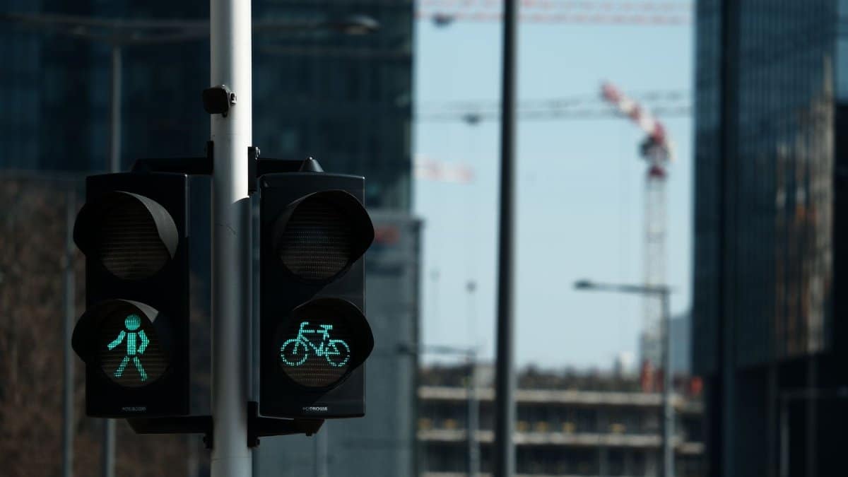 Traffic lights in a modern city with construction cranes in the background, capturing urban development.