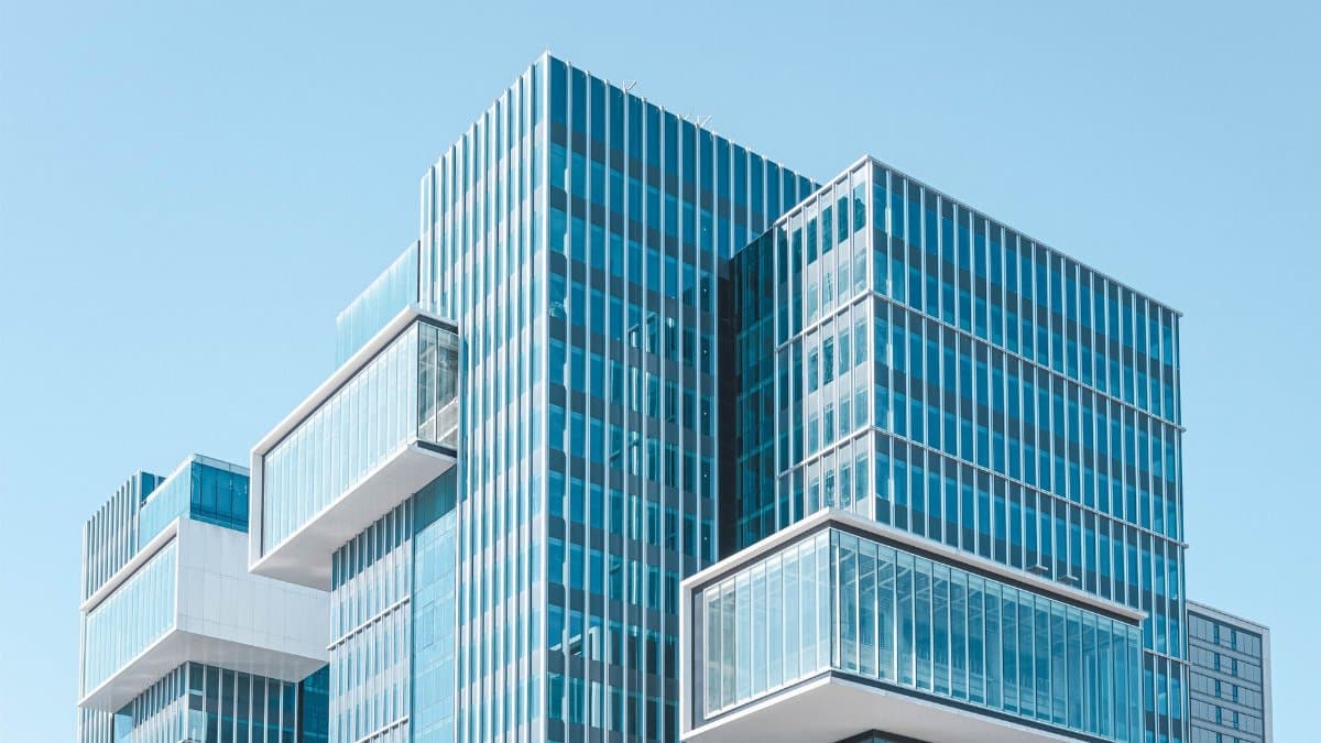 Striking contemporary glass building with unique geometric extensions under clear blue sky.