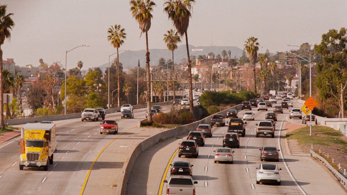Busy highway traffic in Los Angeles with the iconic Hollywood sign visible in the background.