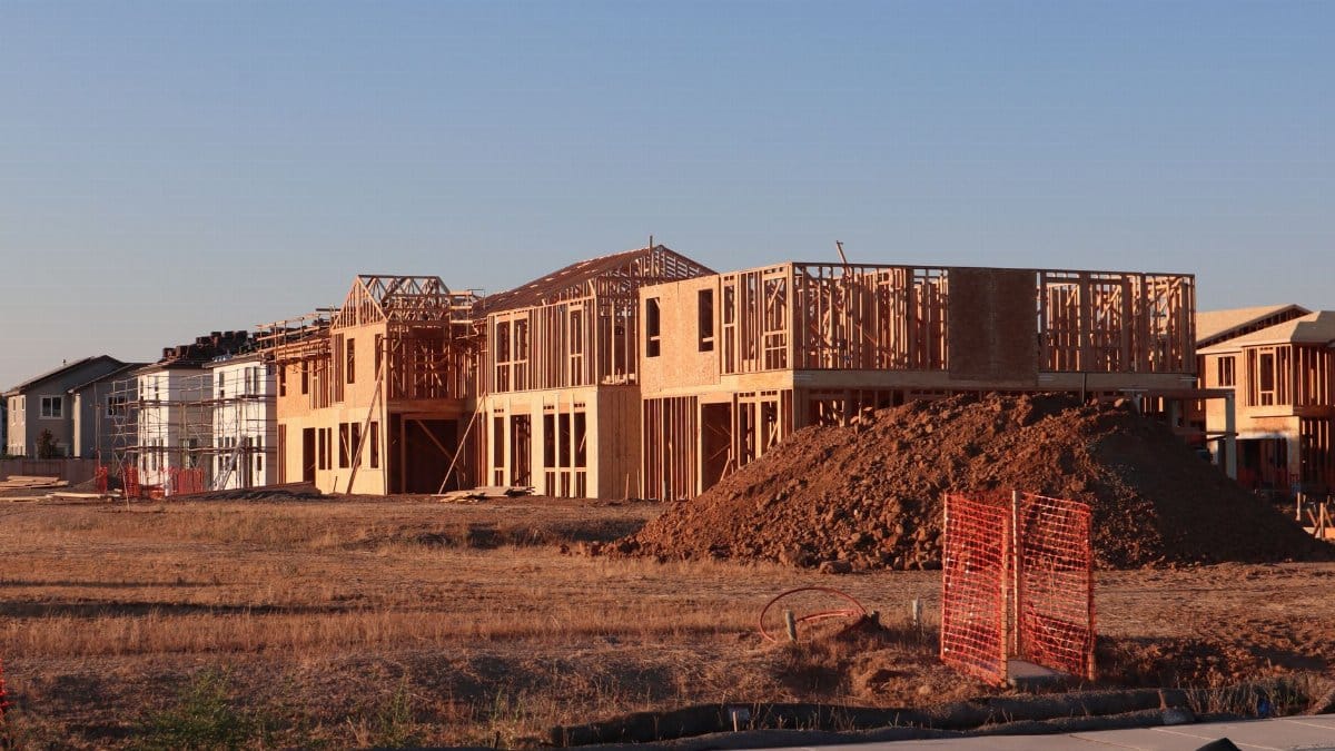 Wooden frames of new homes under construction in Elk Grove, California during sunset.