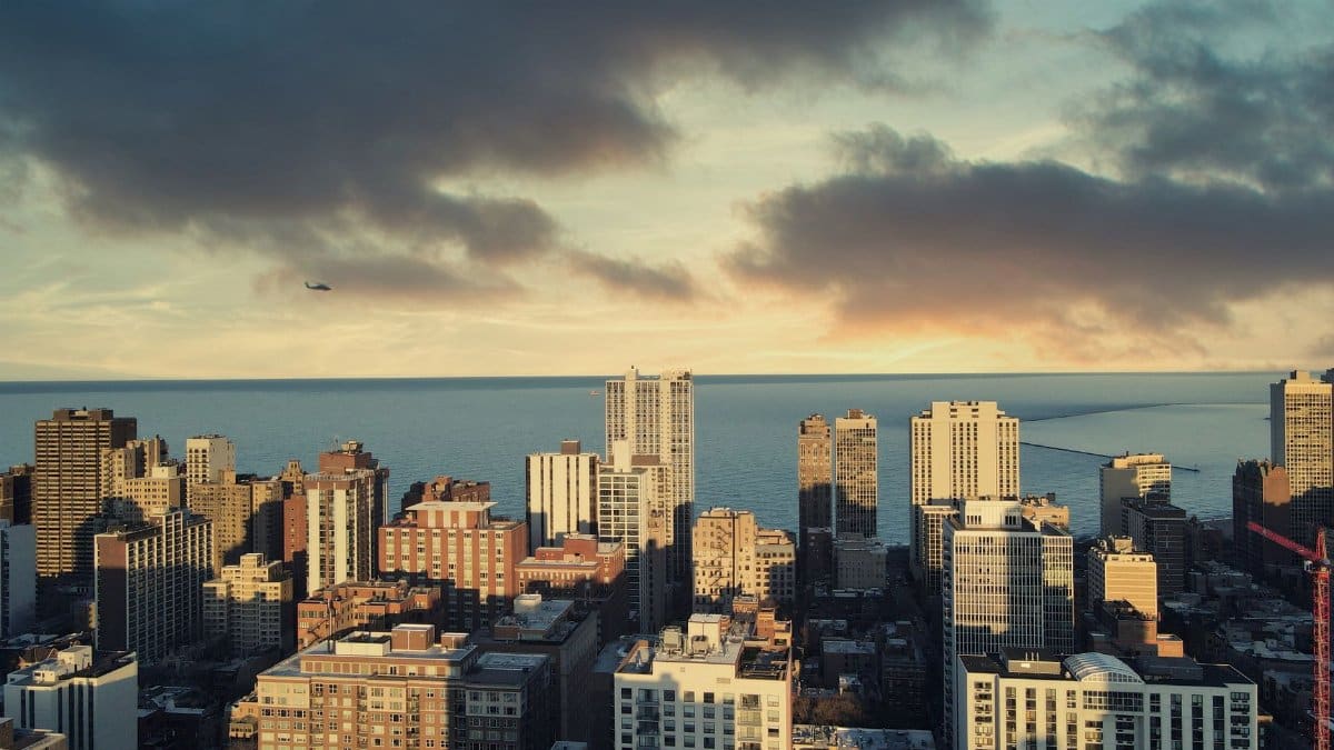 Stunning aerial view of Chicago buildings with Lake Michigan during sunset, clouds enhancing city charm.