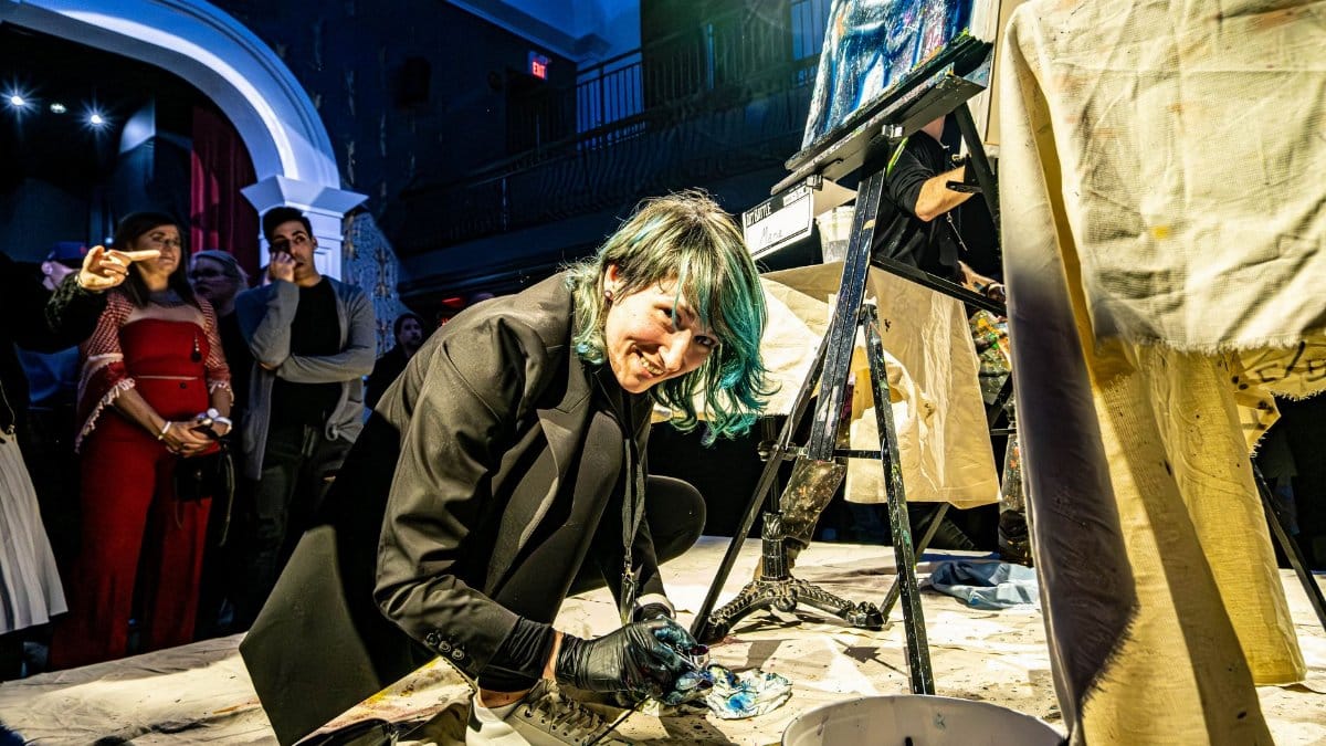 An artist performs live painting in front of an engaged audience during an art show in Toronto.