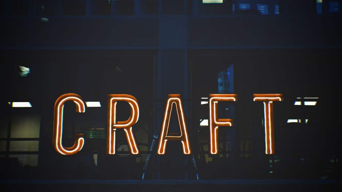 Illuminated neon sign with the word 'CRAFT' glowing against a building backdrop.