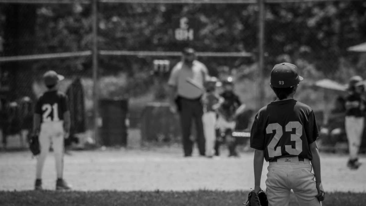 Monochrome scene of young baseball players on a field with uniforms and equipment.