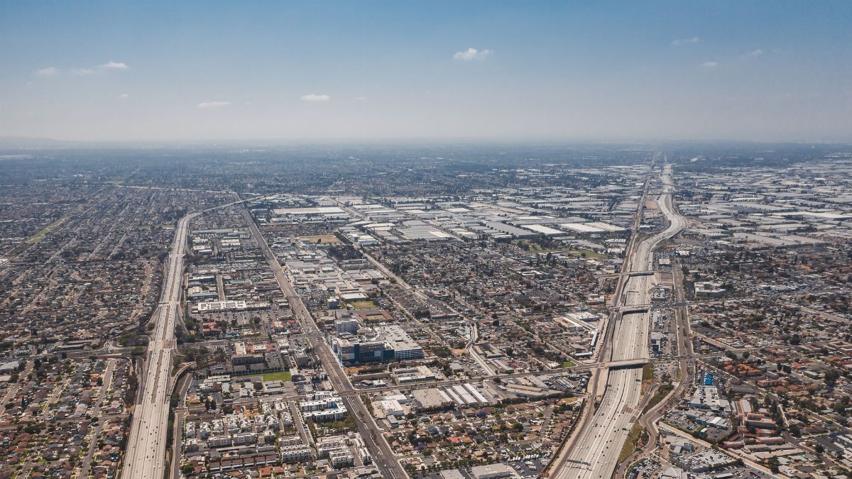 Aerial shot capturing the vast urban expanse and highways of Los Angeles under a clear blue sky.