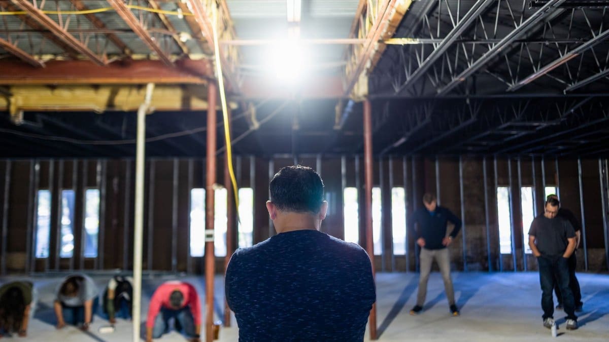 Group of people in a partially constructed building. Indoor setting with natural light.