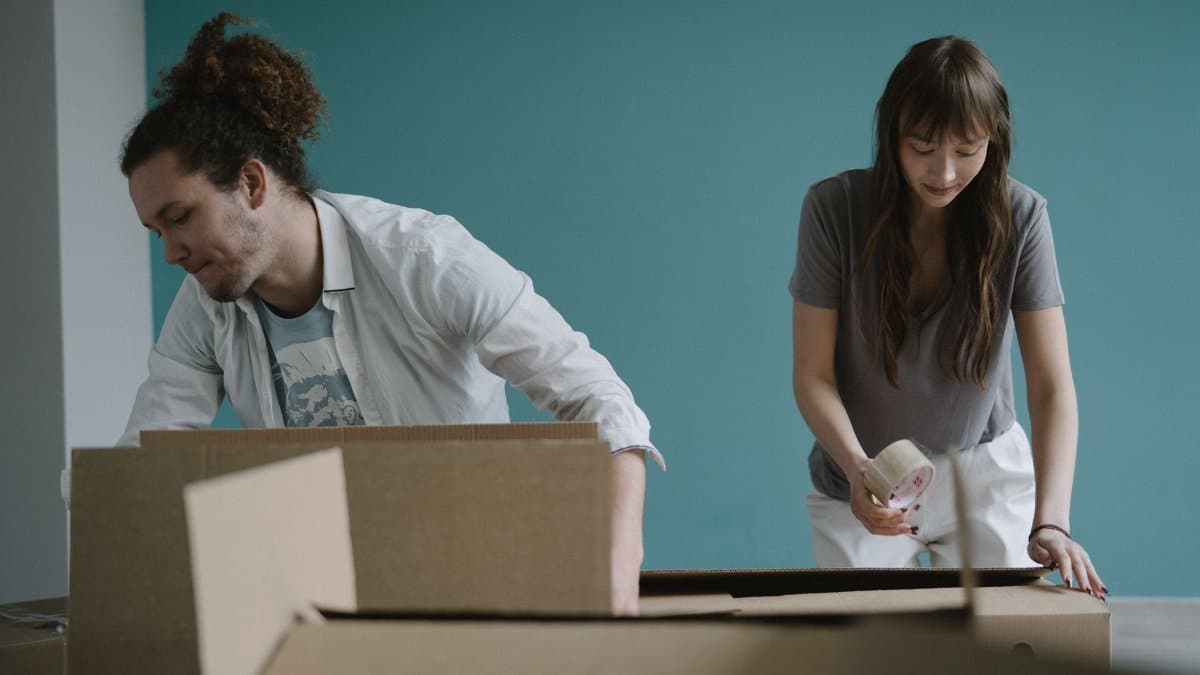 A couple packing boxes together, preparing for a move into their new home.