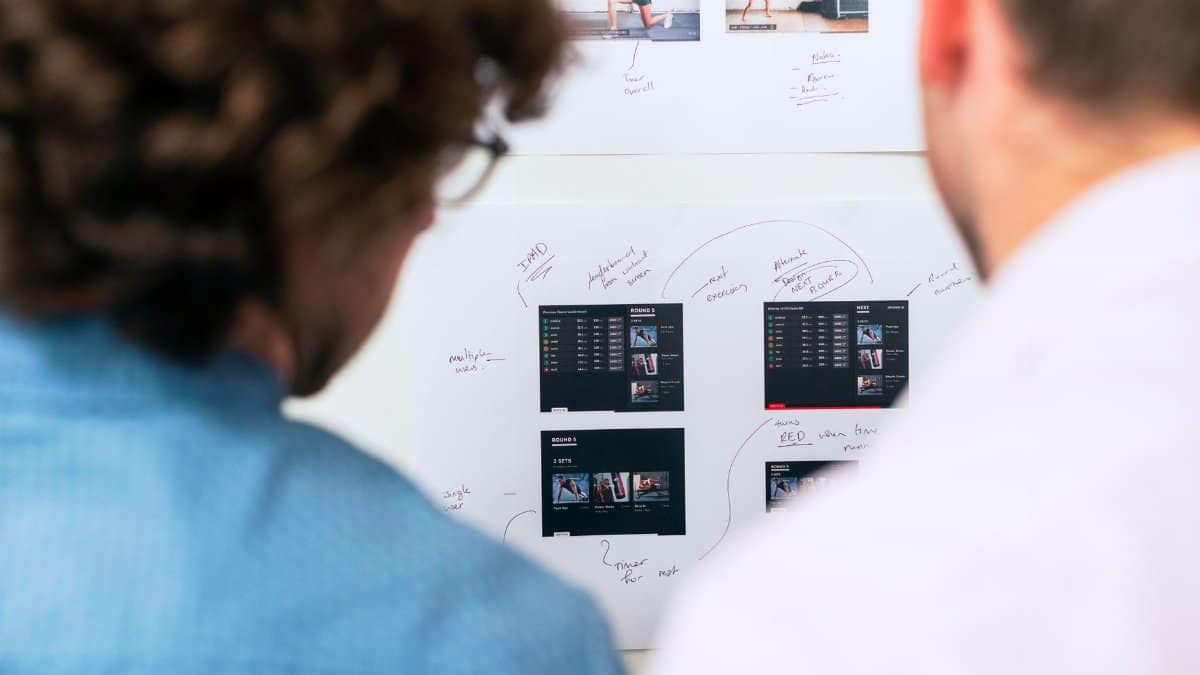 Two business professionals brainstorming and planning software development with a whiteboard in an office.