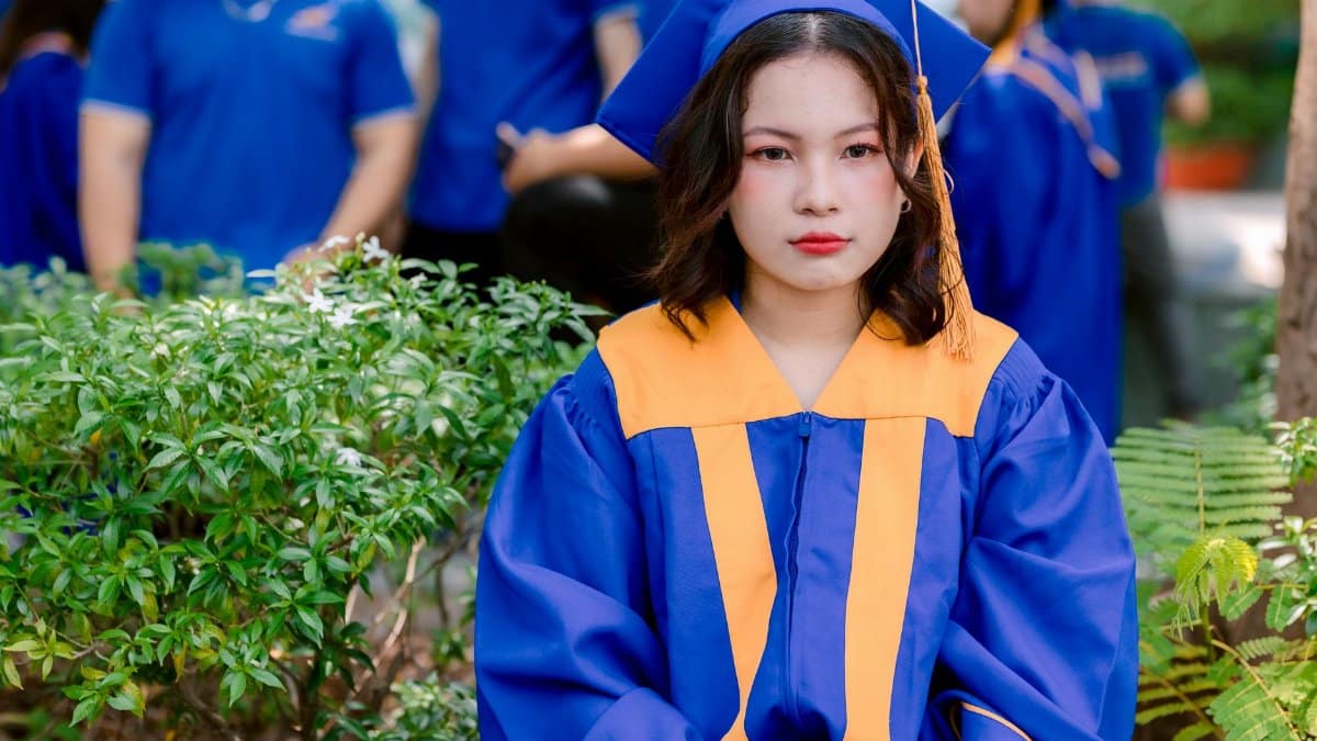 Young woman in graduation attire, posing outdoors during her graduation ceremony.