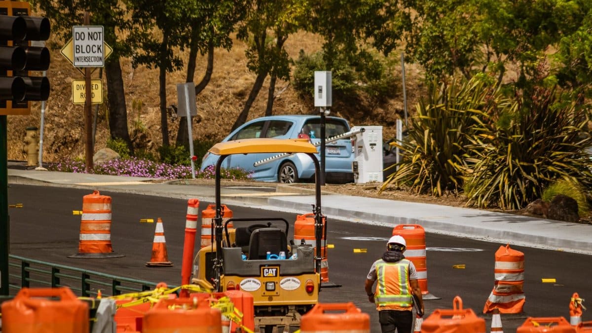 A road construction worker surrounded by safety cones on a street in daylight.