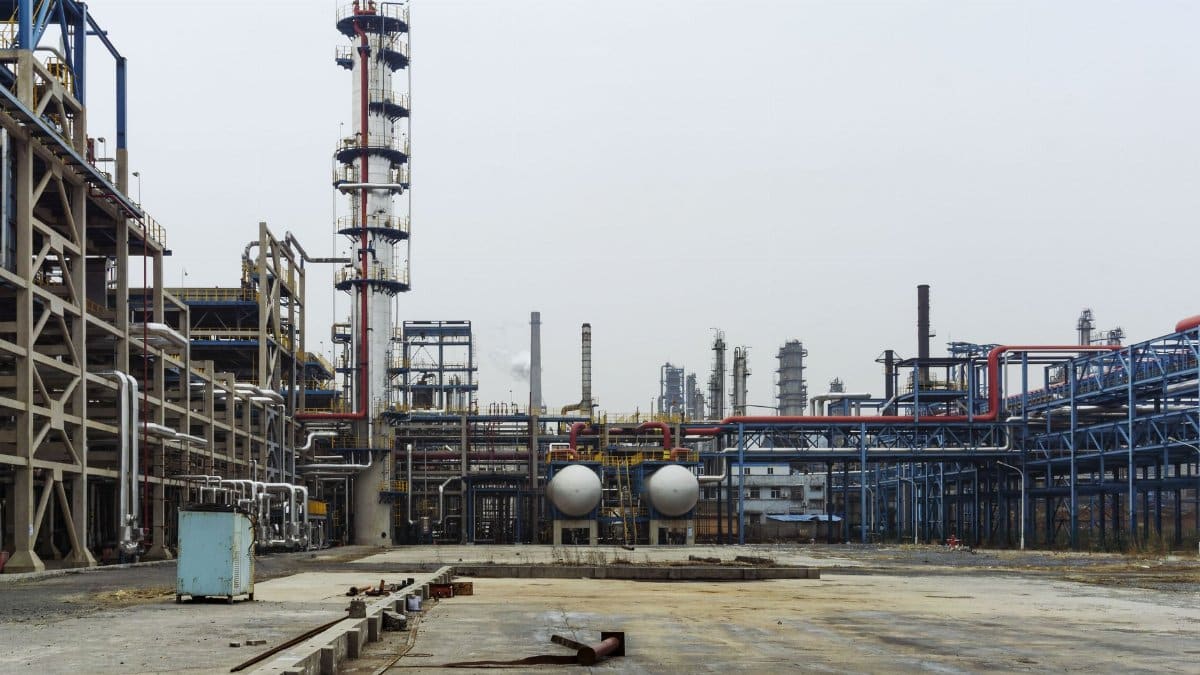 A detailed view of an industrial refinery featuring pipelines and large steel structures.