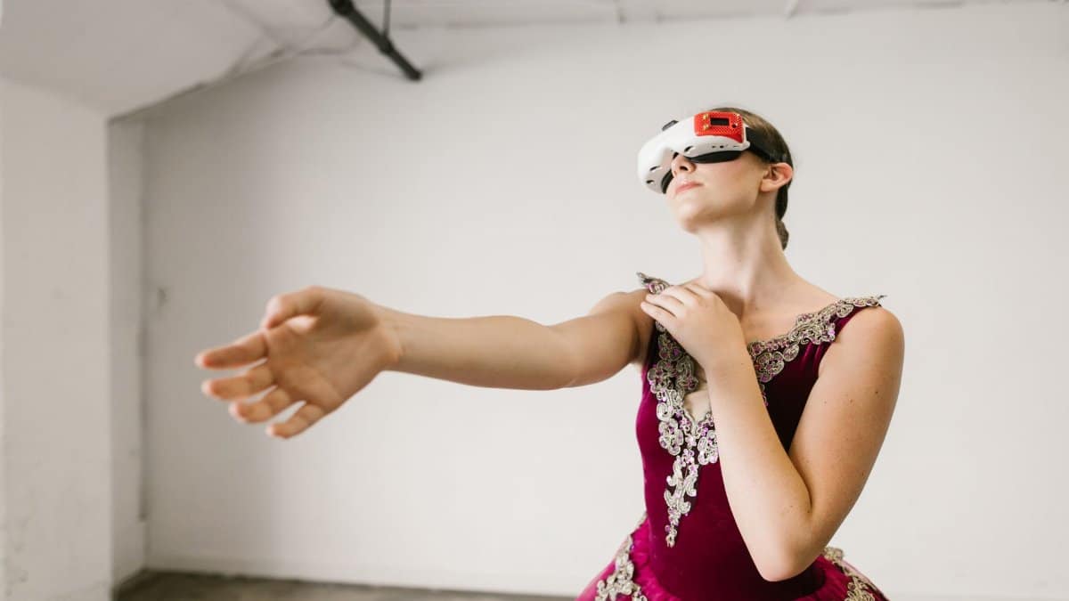 A ballet dancer in a red dress explores virtual reality with a VR headset in an indoor setting.