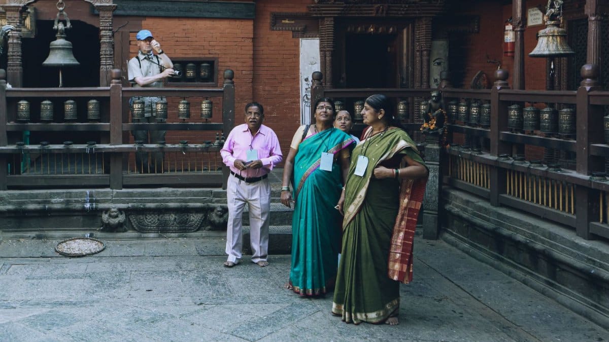 Tourists in traditional attire at a historic temple with ornate architecture.
