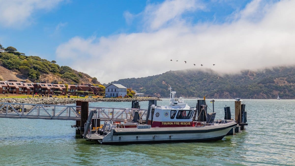 Tiburon Fire Rescue boat docked in a scenic harbor with surrounding hills.