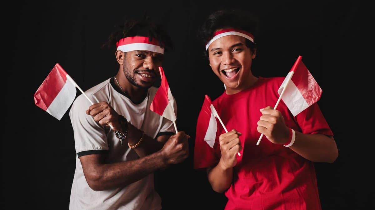 Joyful Indonesian youths celebrating with flags, showcasing national pride and unity.